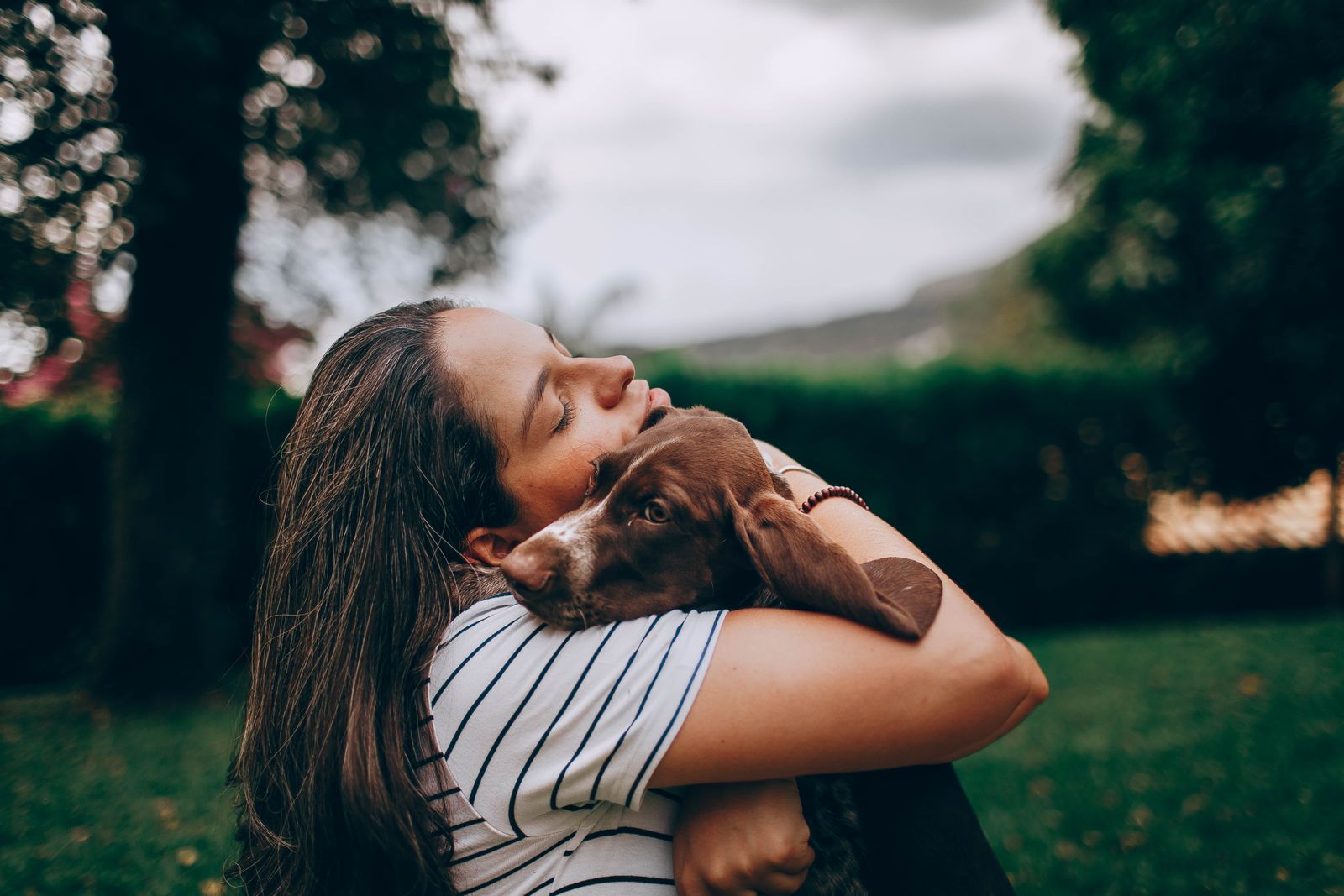 Una mujer abraza a su perro en un jardín